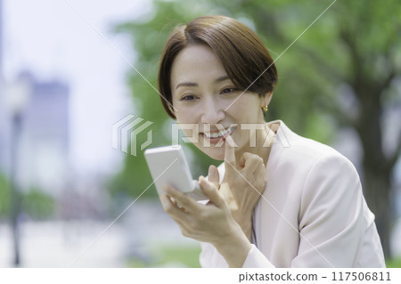公園裡的中年婦女用粉盒看著自己的牙齒 117506811