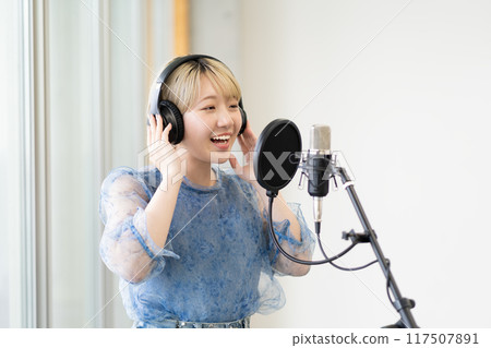 A young woman with short blonde hair singing a song (condenser microphone, recording, vocals, narrator) 117507891