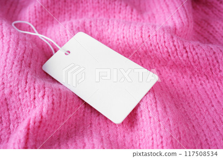 Template of blank clothing label, price tag on pink crumpled knitted sweater background Template of blank clothing label, price tag on pink crumpled knitted sweater background 117508534