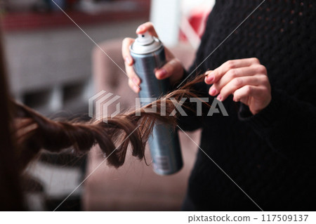 Hairstyle with curls. A close-up curl. A hairdresser in a beauty salon makes a woman's hair with curls using hairspray. The concept of beauty. Hairstyle with curls. A close-up curl. A hairdresser in a beauty salon makes a woman's hair with curls using hairspray. The concept of beauty. 117509137