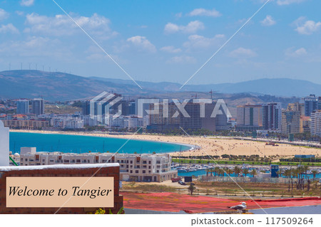Advertising panoramic view of the beach with the ocean from a height with the inscription Welcome to Tangier, to advertise tourist holidays in the resorts of the city, Morocco, Africa 117509264