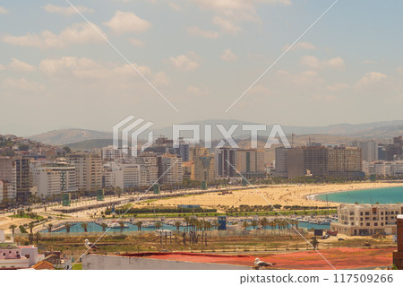 Panoramic landscape of the city with a sandy beach with vacationers on the shore with urban development, mountains and clouds with blue sky Panoramic landscape of the city with a sandy beach with vacationers on the shore with urban development, mountains and clouds with blue sky 117509266