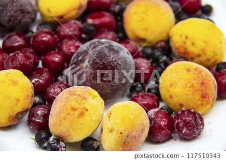 A Berry mix from frozen currant, apricot, plum, cherry. A Frozen Berries from freezer. A sweet background with frozen plum, currant, apricot and cherry. A healthy Berries on the background. 117510343