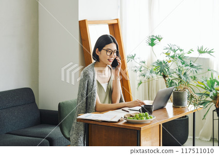 Woman talking on smartphone at home Woman talking on smartphone at home 117511010