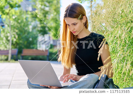 Young female college student typing on laptop computer outdoor Young female college student typing on laptop computer outdoor 117513585