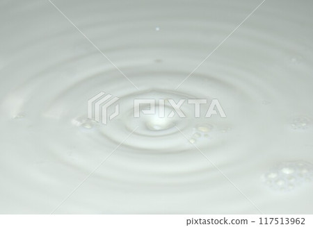 drop of white fresh milk falling to surface splashing and making wave background and texture 117513962