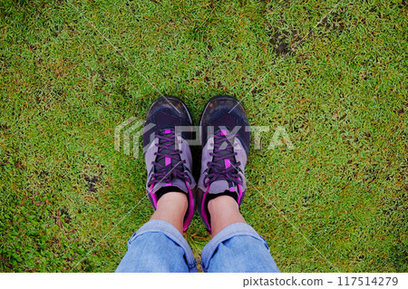 Top view selfie of woman feet and black sneaker stand on the grass field in tropical garden Top view selfie of woman feet and black sneaker stand on the grass field in tropical garden 117514279