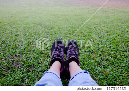 Top view selfie of woman feet and black sneaker stand on the grass field in tropical garden Top view selfie of woman feet and black sneaker stand on the grass field in tropical garden 117514285