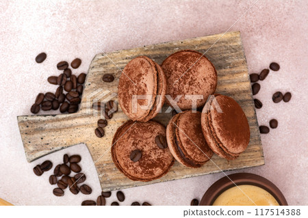 Cup of coffee and chocolate macaroons with coffee beans on wooden board. Top view with copy space Cup of coffee and chocolate macaroons with coffee beans on wooden board. Top view with copy space 117514388