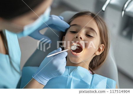 Dentist examining teeth of little girl in dental clinic 117514904