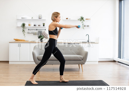 Woman exercising with dumbbells in modern living room 117514928