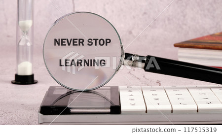 Never stop learning written through a magnifying glass on a gray background in a composition with a calculator, an hourglass and a book Never stop learning written through a magnifying glass on a gray background in a composition with a calculator, an hourglass and a book 117515319