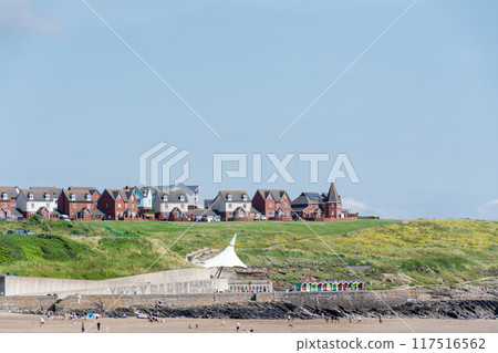 人們在南威爾斯郊區的淺沙灘上放鬆，遠處山上有一排紅磚房 117516562