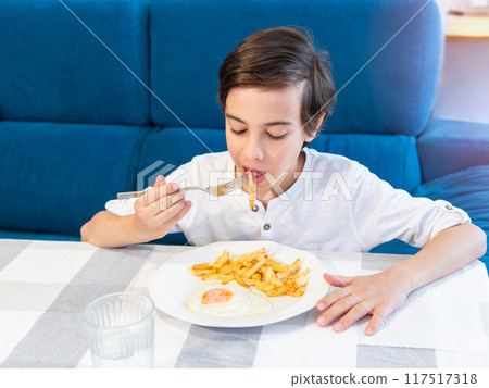 Boy eating meal at table Boy eating meal at table 117517318
