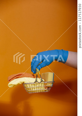 Blue gloved hand holding small store basket with dish sponges Blue gloved hand holding small store basket with dish sponges 117517650