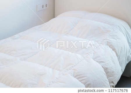 Duvet on a single bed in a white bedroom 117517676