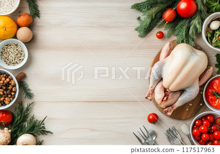 Fresh chicken surrounded by vegetables and herbs on a wooden kitchen countertop 117517963