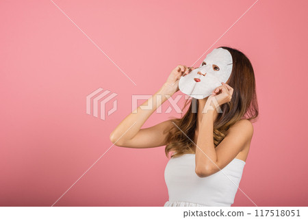 Portrait Asian young woman applying cosmetic paper sheet mask on her face studio shot isolated on pink background, beautiful female with natural makeup cosmetic mask, beauty skin care concept Portrait Asian young woman applying cosmetic paper sheet mask on her face studio shot isolated on pink background, beautiful female with natural makeup cosmetic mask, beauty skin care concept 117518051