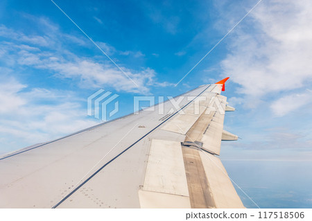 View from the airplane window at a beautiful cloudy sky and the airplane wing View from the airplane window at a beautiful cloudy sky and the airplane wing 117518506