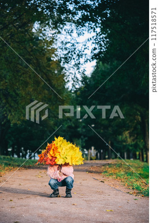 Autumn portrait of little girl with umbrella covered with yellow maple leaves 117518571