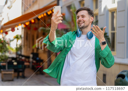 Happy man blogger taking selfie on smartphone communicating video call online with subscribers 117518697