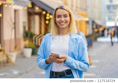 Woman use mobile smartphone typing text messages browsing internet finishing work looking at camera 117518724