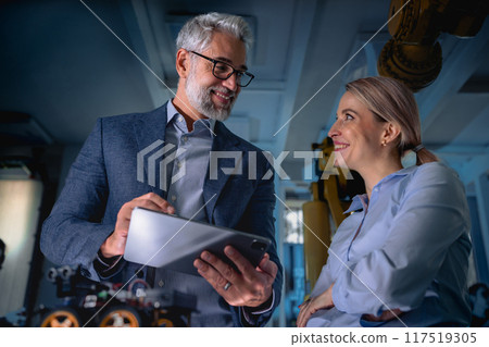 Two robotics engineers working on new project, standing in laboratory. Concept of modern technology in industries, automated processes, automotive Two robotics engineers working on new project, standing in laboratory. Concept of modern technology in industries, automated processes, automotive 117519305