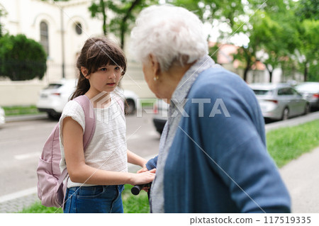 Grandmother explaining to granddaughter how to ride a scooter safely before leaving for school. 117519335