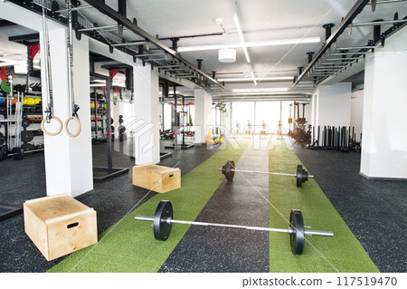 Rows of metal barbells on floor and rack for strength training in gym. 117519470