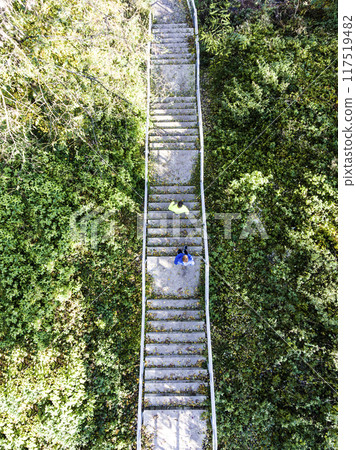 Aerial view of two runners running up the staris in the park. Morning running training for male friends. 117519482