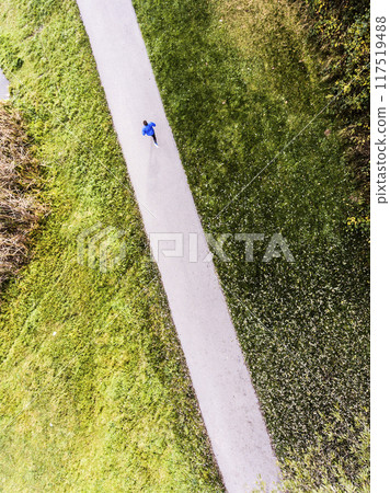 Aerial view of a runner running through the park on a jogging path. Morning running training. Aerial view of a runner running through the park on a jogging path. Morning running training. 117519488