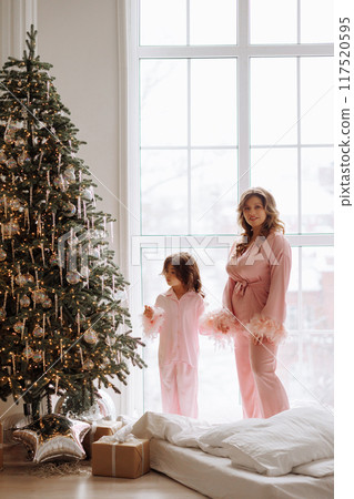 A woman and a child stand in front of a Christmas tree A woman and a child stand in front of a Christmas tree 117520595