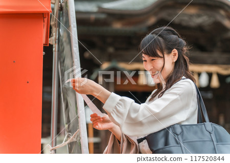 Asian woman drawing a fortune at a shrine Asian woman drawing a fortune at a shrine 117520844