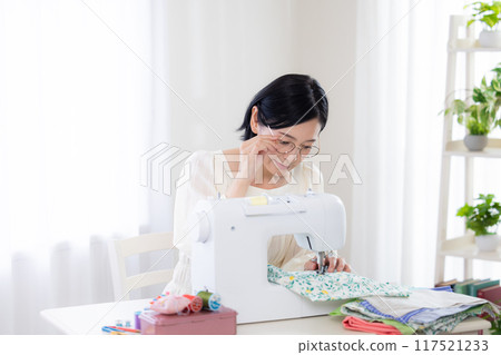 Hobby: Middle-aged woman sewing with a sewing machine Hobby: Middle-aged woman sewing with a sewing machine 117521233