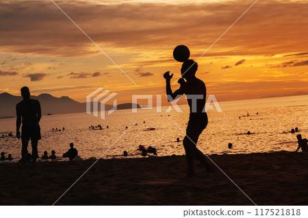 Silhouettes of Asian men ball players playing traditional beach soccer sepak takraw by sea in summer at sunrise 117521818