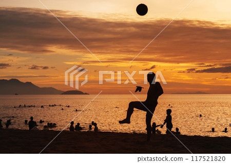 Silhouette of an Asian male player with a ball playing traditional sepak takraw football on beach by the sea at sunrise Silhouette of an Asian male player with a ball playing traditional sepak takraw football on beach by the sea at sunrise 117521820