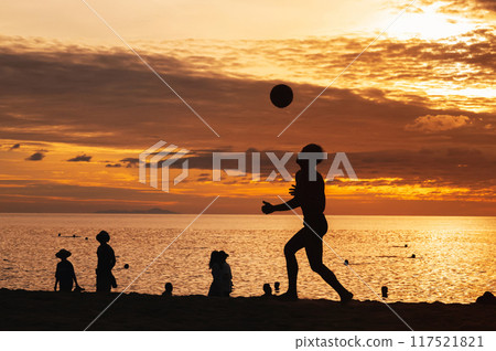 Silhouette of an Asian male player with a ball playing traditional beach football on beach by the sea at sunrise 117521821
