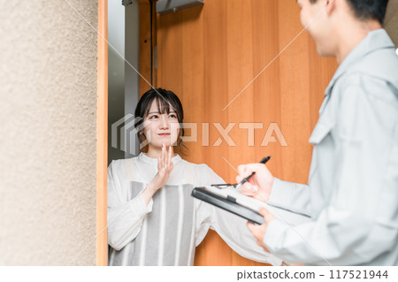 一名家庭主婦在門口拒絕一名穿著工作服的男子來拜訪銷售人員。 一名家庭主婦在門口拒絕一名穿著工作服的男子來拜訪銷售人員。 117521944