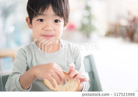 Child eating bread for breakfast, looking at camera 117521998