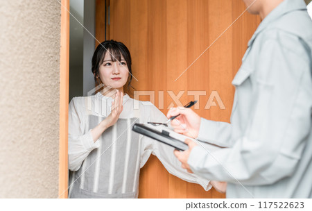 A housewife refuses a man in work clothes who comes to visit her at the entrance 117522623