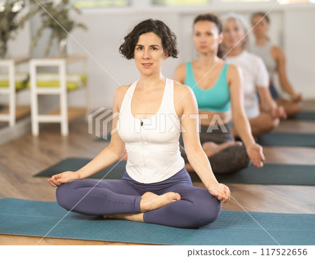 Yoga woman making yoga meditation in lotus pose in fitness studio Yoga woman making yoga meditation in lotus pose in fitness studio 117522656
