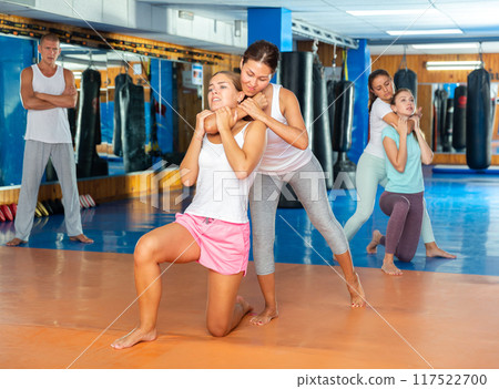 Sporty girls in pairs are training self-defence moves 117522700