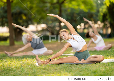 Girl participating in outdoor yoga session in summer park 117522718