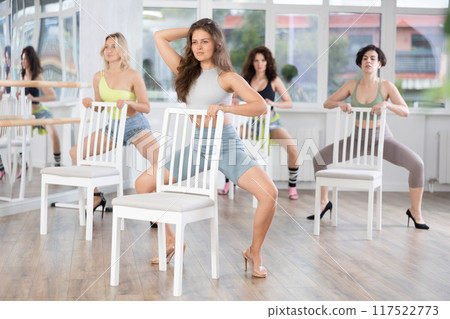 Group of women in high heels rehearsing dance while leaning on chair Group of women in high heels rehearsing dance while leaning on chair 117522773