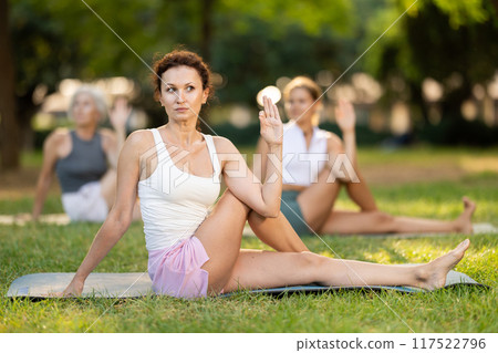 Woman performing Lord of Fishes Pose during yoga session in park 117522796