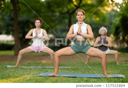 Young female yoga instructor leading outdoor group class Young female yoga instructor leading outdoor group class 117522804