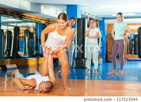 Girl performing hammerlock during self defence training in gym 117523044