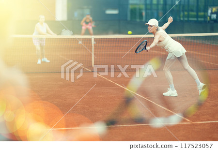 Elderly woman engrossed in tennis game on clay court 117523057