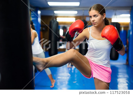 Woman training kicks on punchbag 117523058