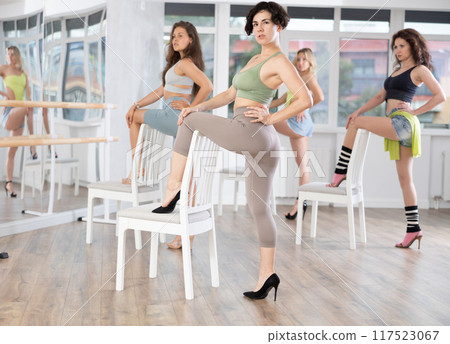 Female dancer in high heels practicing lap dance on chair in studio 117523067